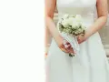 Panna młoda trzyma bukiet białych róż. Kwiaty symbolizują czystość i miłość, a ich znaczenie jest głębokie w dniu ślubu.