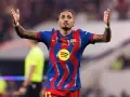 Raphinha, z podniesionymi rękami, świętuje po dołączeniu do FC Barcelony. Jego koszulka zdobi logo Spotify.