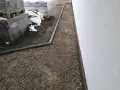 Wykonano opaskę wokół domu z kruszywa, obok ułożone palety z materiałami budowlanymi.
