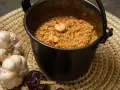 Caldero murciano humeante en olla de hierro, con gambas, ajos y pimientos secos.