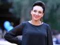 Uśmiechnięta Kinga Dębska w czarnej sukni i ozdobnych kolczykach, pozuje na czerwonym dywanie.