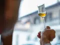 Dłoń trzyma kieliszek ze złotym płynem. To grappa, włoski destylat z wytłoków winogron.