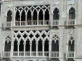 Dettaglio del **Palazzo Cadoro** con le sue finestre a trifora e balconi ornati. Persone osservano dal primo piano.