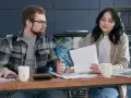 Para analizująca rachunki, jak w psalm 112, z laptopem i kubkami na stole.