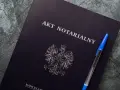 Na ciemnogranatowej okładce widnieje napis "AKT NOTARIALNY" i godło Polski. Obok leży niebieski długopis.