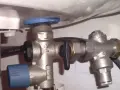 Un réducteur de pression, comme ce dispositif métallique avec une poignée noire, sert à réguler la pression de l'eau dans une installation.