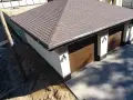 Nowy dach papa na garażu z brązowymi drzwiami i ozdobnymi słupkami.
