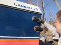 Man applicerar keramisk lackskyddsbehandling på en blå båt med texten "LANDAU 20".