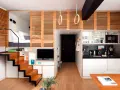 Estudio moderno de piso 25 metros cuadrados con cama elevada, cocina compacta, zona de TV y escaleras de madera.
