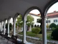 Portico con archi e colonne bianche, panchine e un giardino interno. Per sapere isola degli armeni come arrivare, visita questo luogo tranquillo.