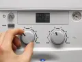 Mano che regola la caldaia spenta senza corrente. Il display mostra 49°C.