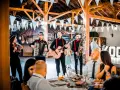 Zespół grający na weselu, z akordeonem, gitarą i saksofonem. W tle widać gości i dekoracje. Idealni do oprawy muzycznej imprez, znają teksty piosenek biesiadnych i weselnych.