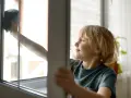 Chłopiec z uśmiechem na twarzy myje okno. To część jego listy obowiązków domowych dla dzieci.