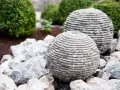 Dwie kamienne kule z betonu, przypominające ułożone krążki, stanowią element wodnej instalacji ogrodowej. Dowiedz się, jak zrobić kulę z betonu.