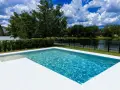 Agua de piscina blanquecina, cristalina y refrescante, con reflejos del cielo azul y nubes blancas. Un oasis de paz.