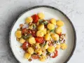 Gnocchi z pomidorkami koktajlowymi, szałwią i orzechami laskowymi, posypane parmezanem. Pyszne danie na obiad.