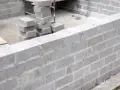 Budowa fundamentów z bloczków betonowych, stosy bloczków na placu budowy.