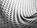 Composition d'image abstraite en noir et blanc, montrant une structure métallique aux formes ondulées et répétitives, créant un jeu d'ombres et de lumières.