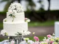 Elegancki, dwupiętrowy tort weselny ozdobiony bukietem białych i różowych, **jakie żywe kwiaty na tort** dodają mu uroku.