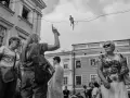 Street foto: tłum na ulicy obserwuje śmiałka balansującego na linie.