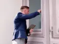 Mężczyzna w garniturze puka do drzwi, trzymając teczkę. Zastanawia się, ile zabierze komornik z premii.