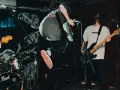 Ein Gitarrist springt auf der Bühne, während ein Bassist spielt. Das ist Rockmusik in Aktion!