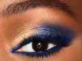 Un œil aux smoky eyes bleus intenses, rehaussé de fard doré et de paillettes. Un regard captivant.