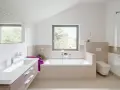Salle de bain moderne avec baignoire, lavabo, douche vitrée et toilette suspendue.