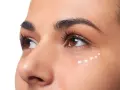 Application de crème hydratante sous les yeux, parfaite pour le maquillage hivernal.