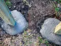 Holzpfosten werden in frisch gegossenen Beton gesetzt, um einen stabilen Zaun zu bauen. Das Einbetonieren der Zaunpfosten sorgt für Langlebigkeit.