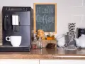 Máquina de café, taza, galletas y un letrero que dice "my Home Coffee bar". Todo listo para disfrutar de un momento de relax en tu zona de cafe en la cocina.