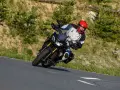Motocyklista w kasku na zakręcie górskiej drogi. Planujesz podróż na Korsykę? Sprawdź ceny paliwa i noclegów!