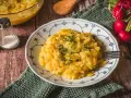 Omas Kartoffelsalat, ein Klassiker auf dem Holztisch, garniert mit Petersilie. Daneben Radieschen und Salzstreuer.