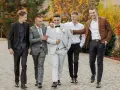 Pięciu mężczyzn w eleganckich garniturach idzie razem. Świetna inspiracja, jak się ubrać na wesele!