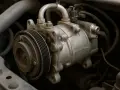 Detailaufnahme eines Auto-Klimakompressors. Die Klimaanlage im Auto funktioniert nicht, was auf ein Problem mit diesem Teil hindeuten könnte.