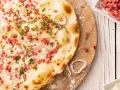 Flammkuchen vegetarisch mit Speckwürfeln, Zwiebelringen und Schnittlauch. Ein Genuss für jeden Gaumen!