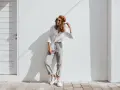 Modello con cappello marrone e occhiali da sole, indossa una camicia bianca e pantaloni grigi. Un esempio di abbinamenti outfit grigio casual e chic.