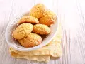 Biscotti con farina di mais dorati e friabili, serviti in un piatto bianco su un tovagliolo giallo.