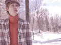 Giovane uomo con berretto e giacca a quadri, in un paesaggio innevato. La sua fantasia check si abbina al freddo.