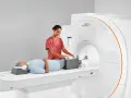 Pacjent leży na łóżku rezonansu magnetycznego, a technik przygotowuje jego nogi do badania. To właśnie mri co to za badanie, które pozwala zajrzeć do wnętrza ciała.