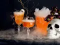 Två orangea drinkar med skum och en dödskalle, perfekt för en kuslig halloween-kväll.