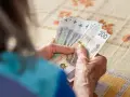Dłonie starszej osoby liczą banknoty 200 zł. Tabela 13 emerytura 2026 może zawierać podobne kwoty.