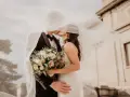 Młoda para całuje się pod welonem, trzymając bukiet. To jak wiersz dla młodej pary, pełen miłości i nadziei.