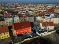 Widok z lotu ptaka na miasto, gdzie leży Ostrów Wielkopolski. Widać kolorowe kamienice, dachy i samochody.
