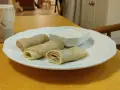 Na talerzu leżą zwinięte naleśniki z mąki owsianej, obok miseczka z kremowym sosem. Idealne na zdrowe śniadanie.