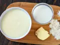 Zutaten für eine Mehlschwitze: Butter, Mehl, Milch und Salz auf einem Holzbrett.