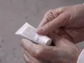 Mani che tengono un tubetto di crema, leggendo gli ingredienti che includono l'acido miristico, per una pelle nutrita.