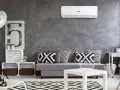 Un moderno soggiorno con divano grigio, cuscini geometrici e un **condizionatore** a parete. Il significato è comfort e stile.