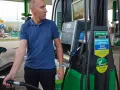 Mężczyzna dokonuje tankowania swojego samochodu na stacji paliw. W ręku trzyma pistolet do paliwa, gotowy do rozpoczęcia procesu.