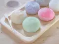 Kolorowe mochi na drewnianej tacce. Chcesz wiedzieć, jak zrobić mochi? Te słodkie kuleczki wyglądają pysznie!
